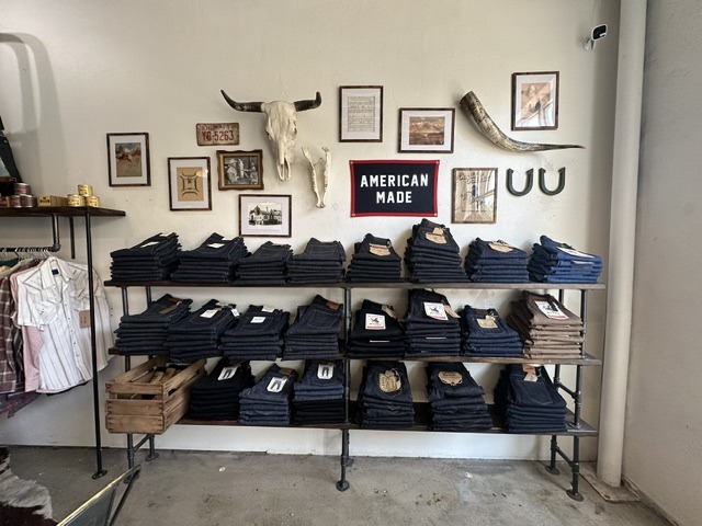 Folded denim display at Brass Tacks Provisions with an American Made sign and western decor