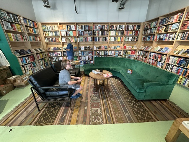 Customers in a reading area with a green sofa and bookshelves at Commonplace Books in Midtown OKC.