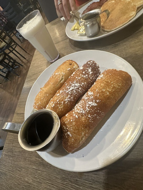 Rolled crepes with powdered sugar and syrup at Eggceptional Cafe.