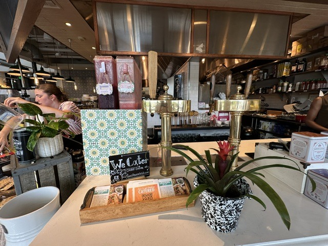 Flower Child counter area with plants, catering cards, and staff behind the service counter.