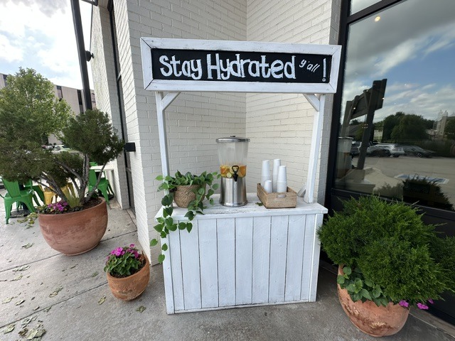 Outdoor hydration station at Flower Child with a sign that says Stay Hydrated y’all.