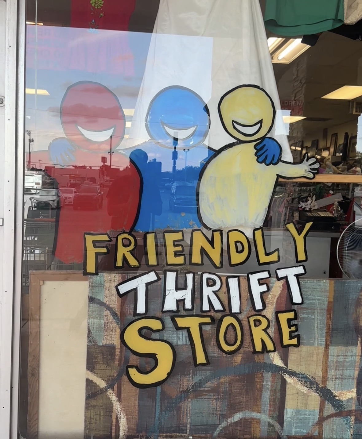 Hand-painted Friendly Thrift Store window with smiling colorful figures.