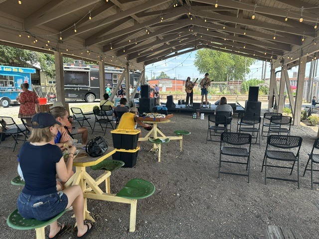 Musicians performing under a shaded pavilion at the OKC Farmers Market Summer Solstice Festival.