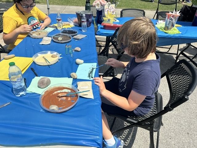 Children painting rocks at a craft table during the OKC Farmers Market Summer Solstice Festival.