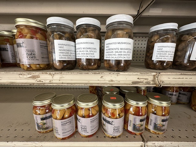 Jars of sweet baby corn and marinated mushrooms on shelves inside Pinata Store