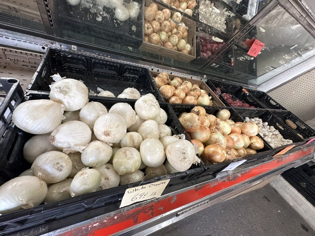 Bins of white, yellow, and red onions for sale inside Pinata Store near the OKC Farmers Market