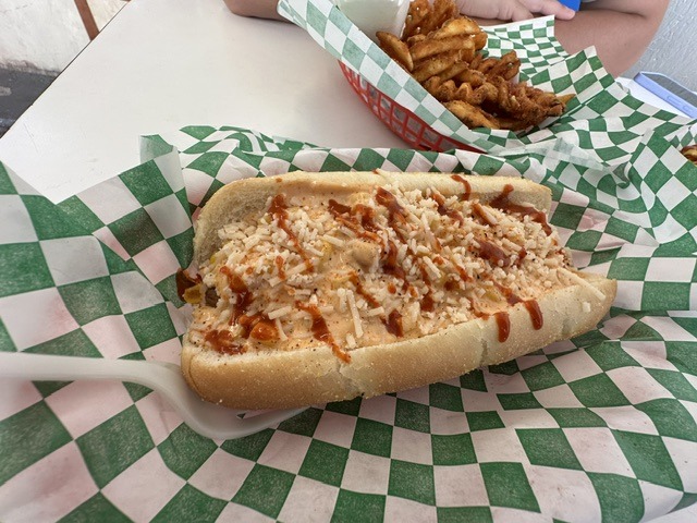Loaded elote-style vegan hot dog at Shaq’s Vegan Dogs in Oklahoma City with waffle fries in the background