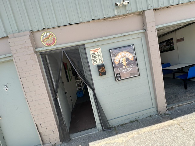Entrance to Shaq’s Vegan Dogs in Oklahoma City with open sign, hours, and branded poster