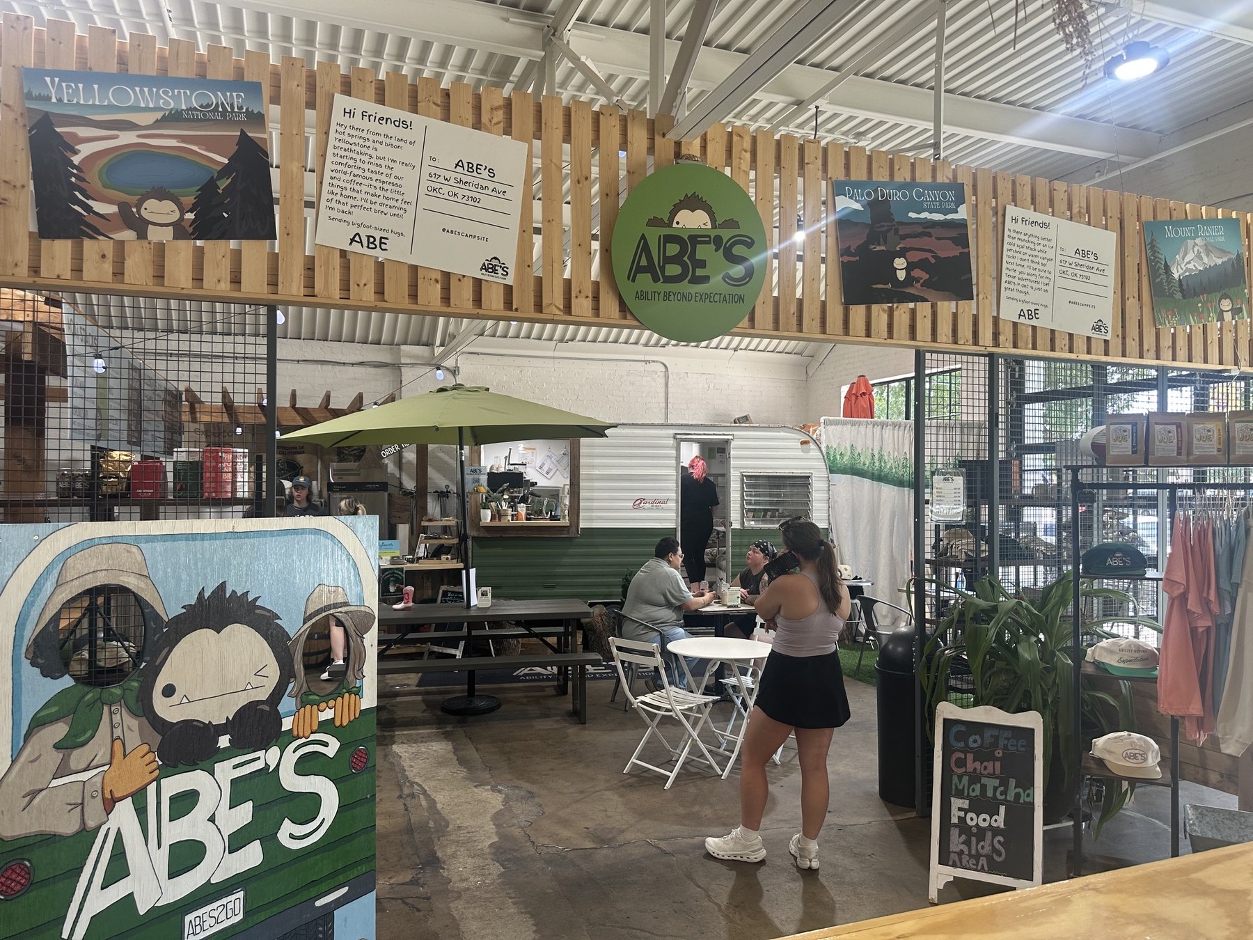 Wide view of ABE’s Campsite inside Sailor & the Dock in Oklahoma City with a camper counter, seating, merch, and customers.