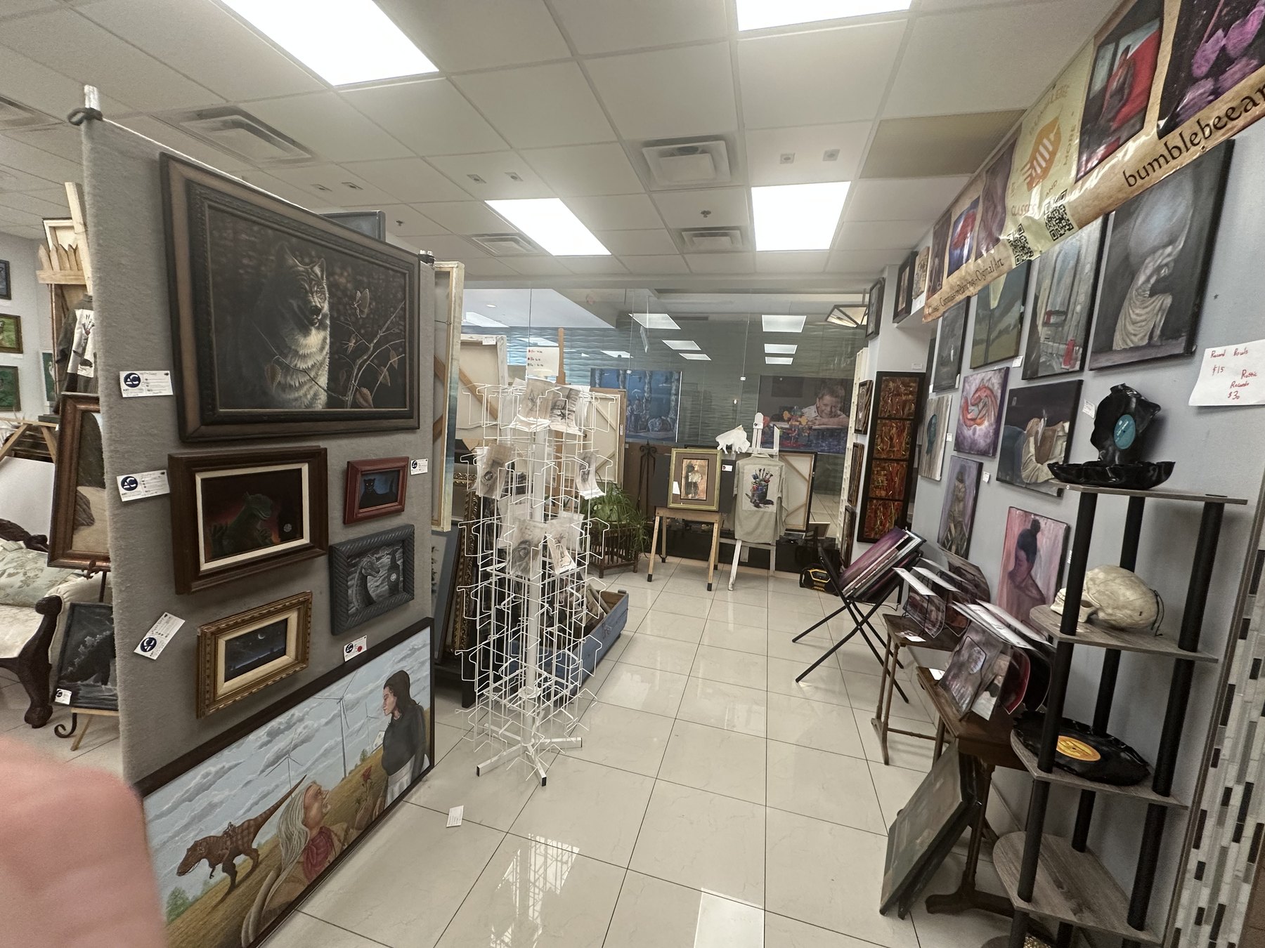 Side room at Art Central Gallery with paintings, print racks, wall displays, and mixed media artwork