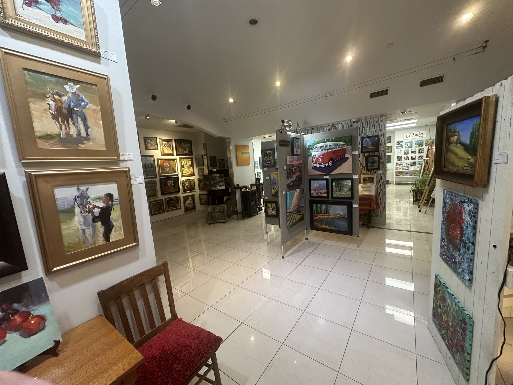 Wide interior view of Art Central Gallery with paintings on walls and freestanding display panels