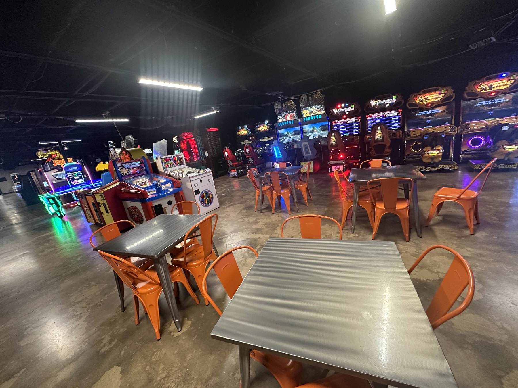 Seating area with orange chairs and arcade games in the background at Cactus Jack’s in Oklahoma City.