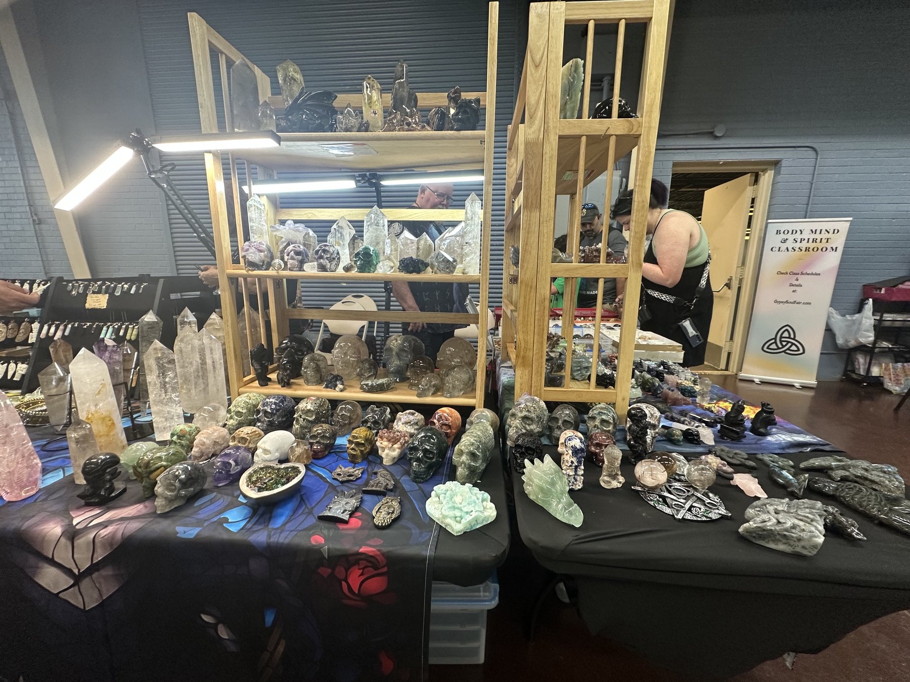 Crystal skulls, carved stones, crystal points, and jewelry displayed at a Gypsy Soul Fair vendor booth.
