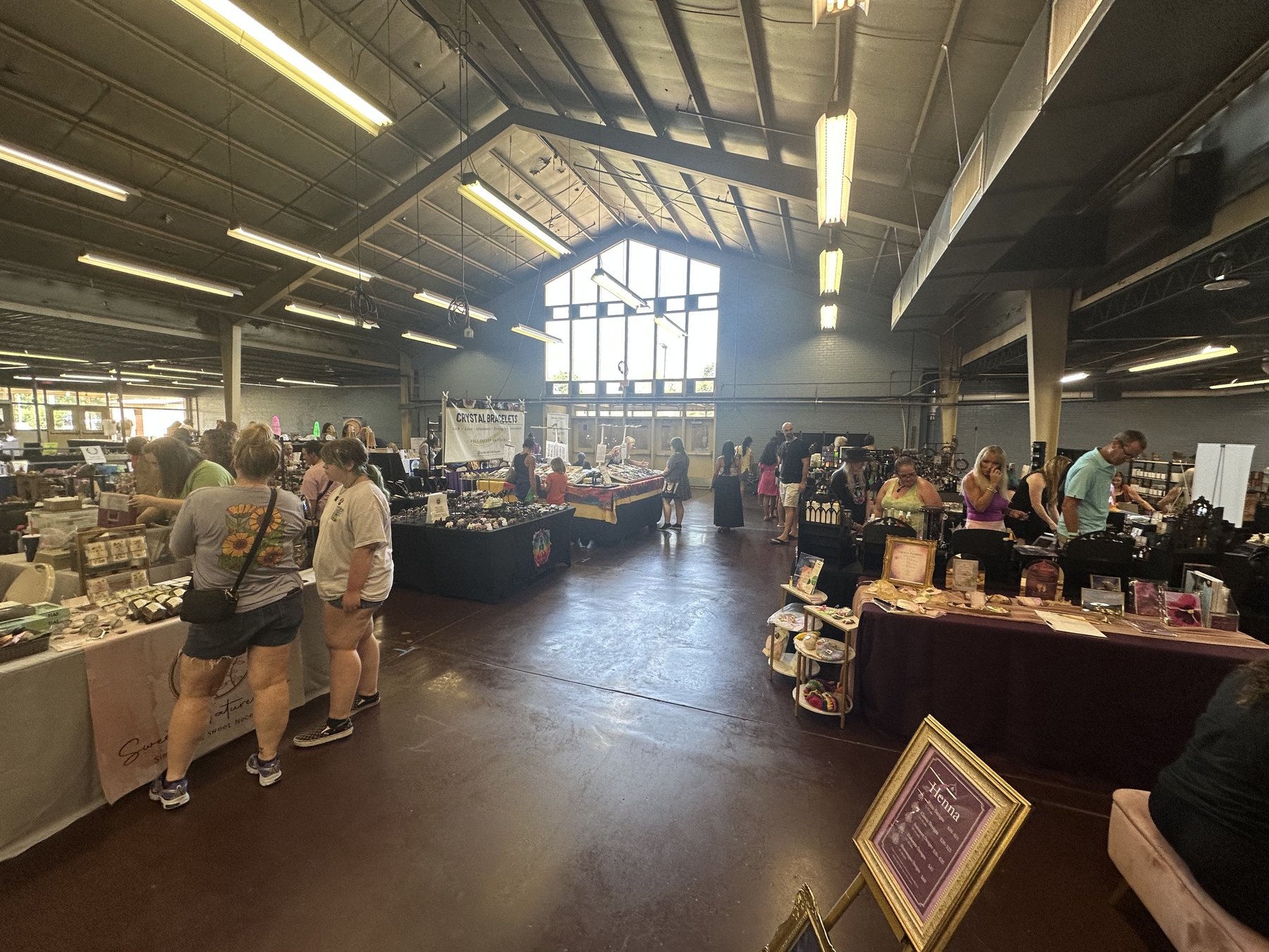 Visitors walk through an indoor hall lined with vendor booths at the Gypsy Soul Fair in Oklahoma.