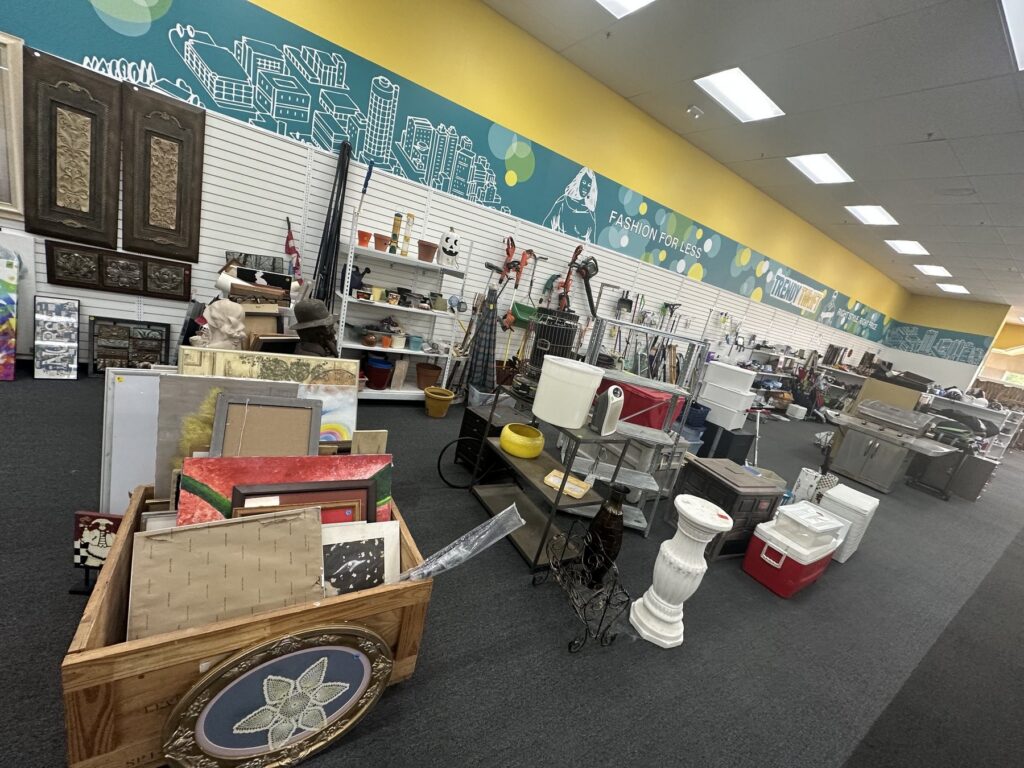 Home decor and housewares area at Trendy Thrift in Norman with framed art, small furniture, coolers, and household items.