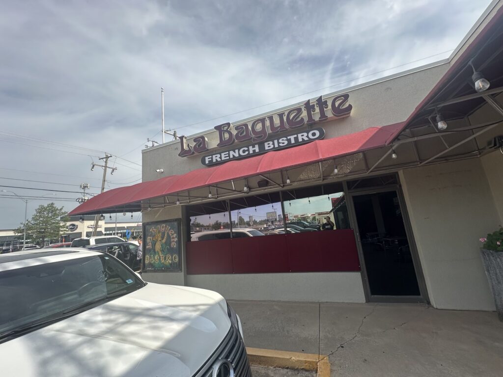 Exterior of La Baquette French Bistro in Oklahoma City with red awning and storefront sign.