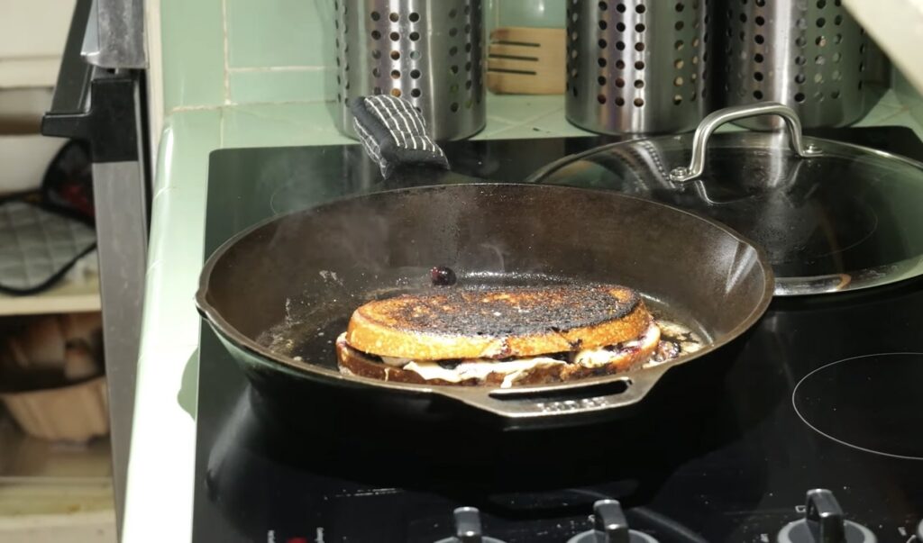 Blueberry brie grilled cheese melting in a cast-iron pan on a stovetop.