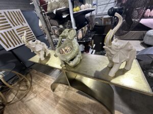 Elephant decor pieces and accessories displayed on a metallic console table at Timeless Furniture in Oklahoma City
