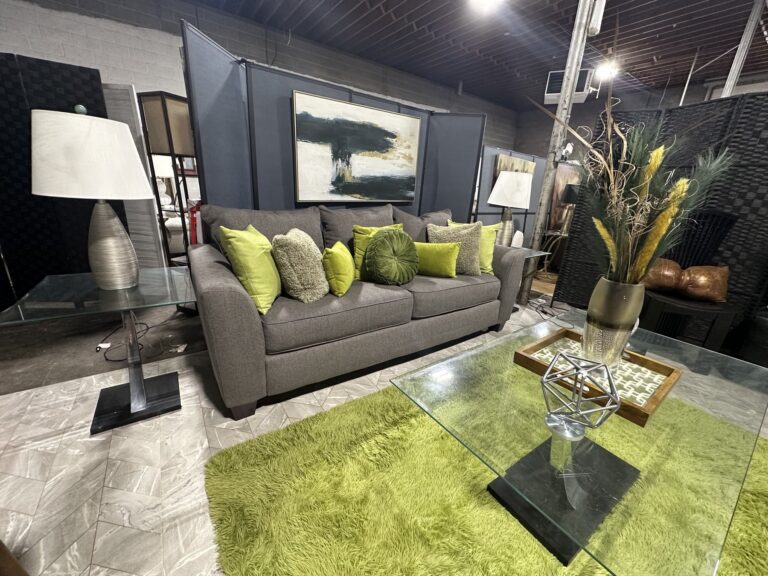 Gray sofa with green pillows, glass tables, lamps, green rug, and abstract wall art at Timeless Furniture in Oklahoma City