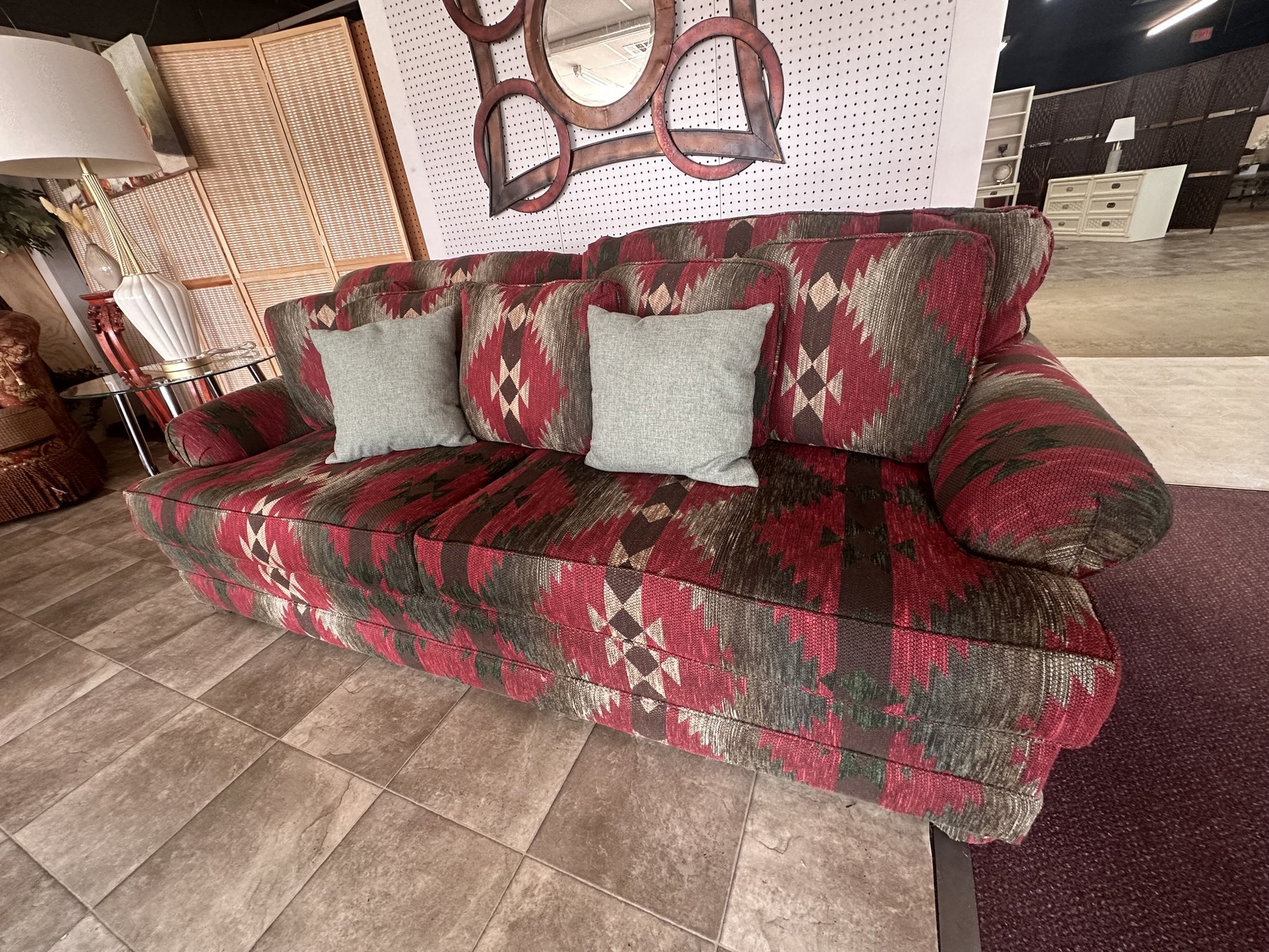 Red patterned sofa with gray pillows inside the Timeless Furniture OKC showroom.