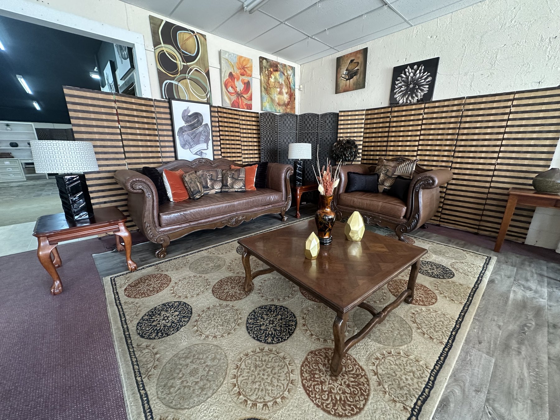 Staged living room set with brown leather sofa, chair, coffee table, rug, lamps, and wall art at Timeless Furniture in OKC.