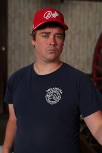Participant in an Oklahoma Fire Museum shirt wears a red Oklahoma cap during a portrait fundraiser shoot.