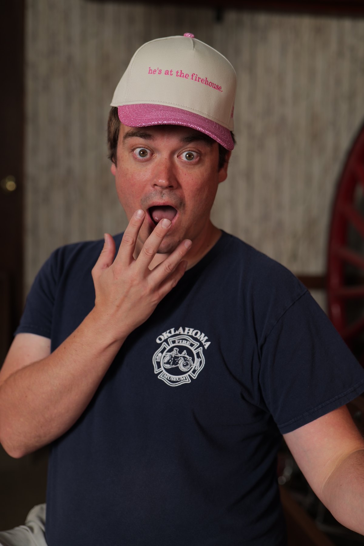 Participant in an Oklahoma Fire Museum shirt wears a pink-brimmed hat that says he is at the firehouse.