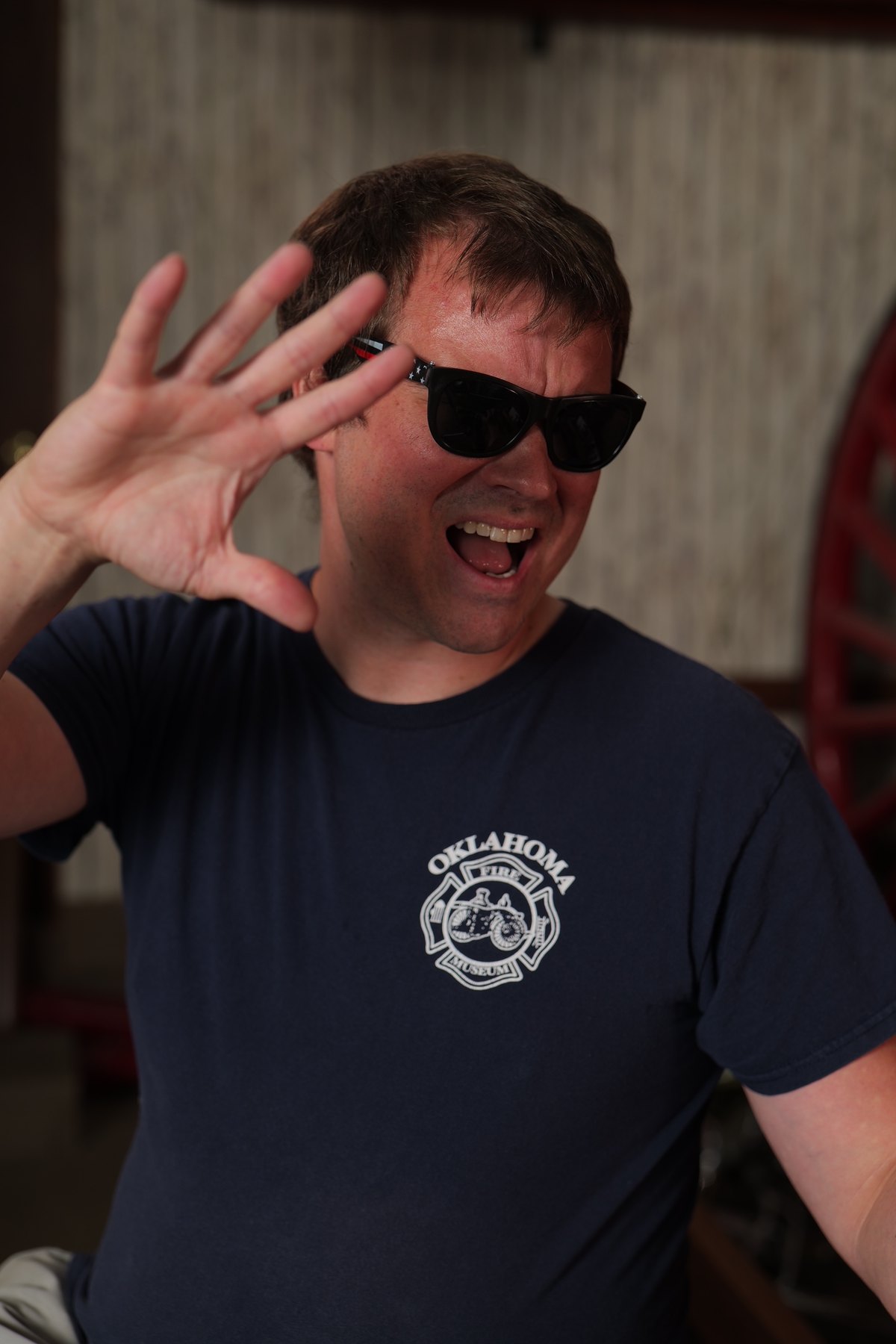 Participant in sunglasses waves during an Oklahoma Fire Museum portrait fundraiser photo session.
