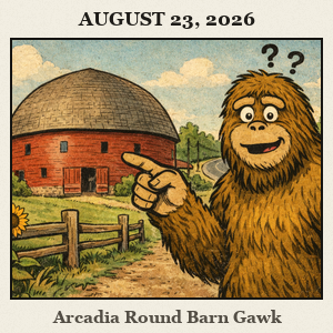 Bigfoot with a puzzled expression points toward the historic red Arcadia Round Barn under a wide prairie sky