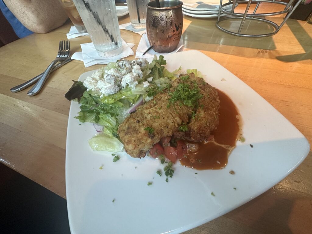 Breaded chicken entree with sauce and a side salad at Upper Crust Wood Fired Pizza in Nichols Hills.