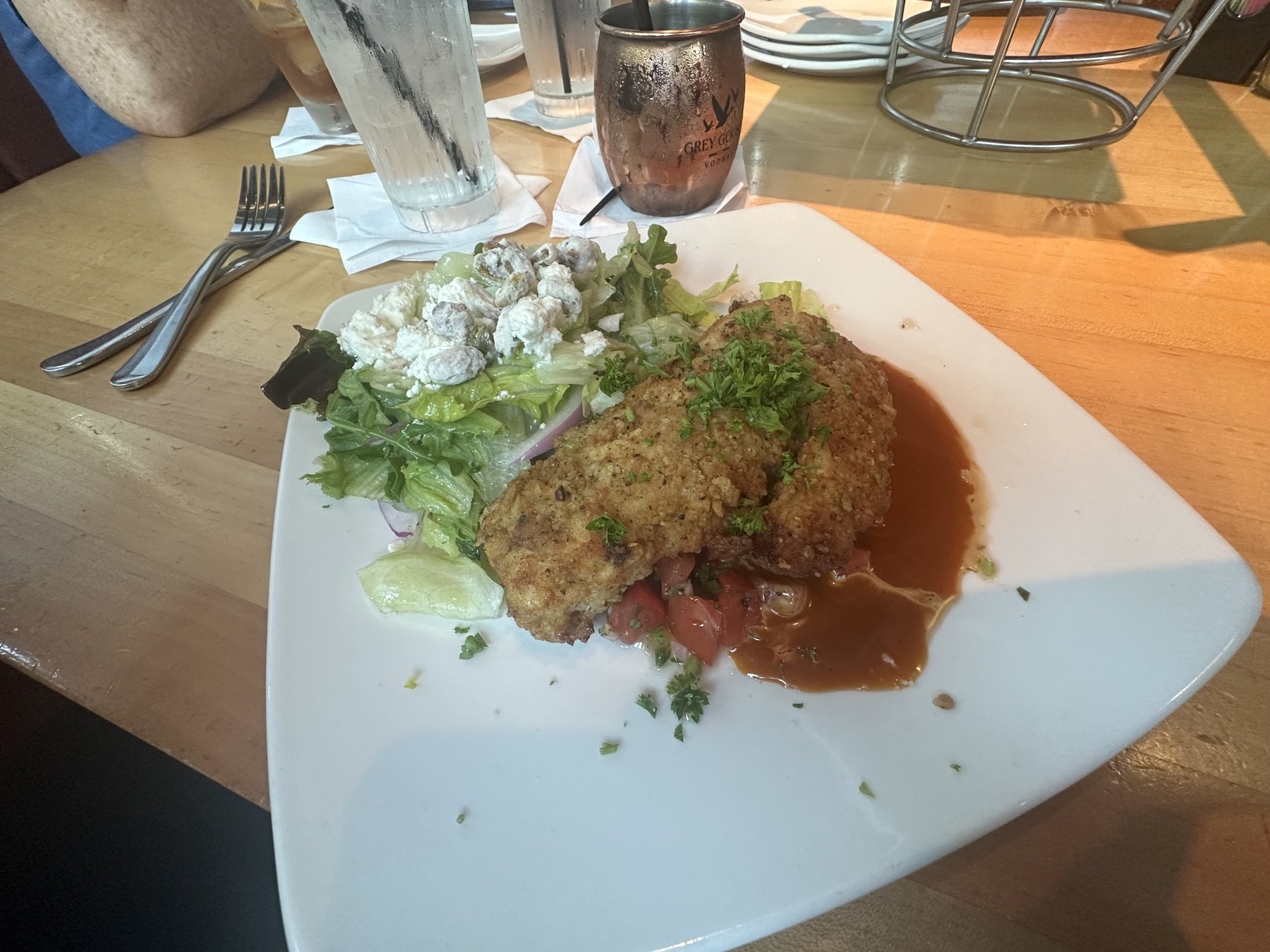 Breaded chicken entree with sauce and a side salad at Upper Crust Wood Fired Pizza in Nichols Hills.