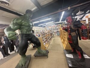 Life-size Hulk and Deadpool statues inside Gardner’s Used Books in Tulsa, with rows of bookshelves behind them.
