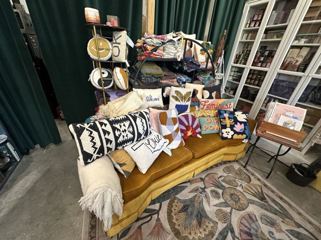 Colorful handmade pillows and textiles displayed on a mustard-yellow couch at Made Modern Handmade in Tulsa