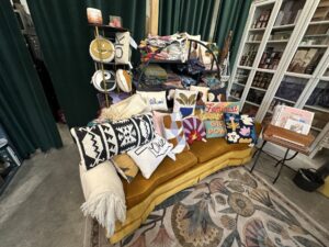 Colorful handmade pillows and textiles displayed on a mustard-yellow couch at Made Modern Handmade in Tulsa