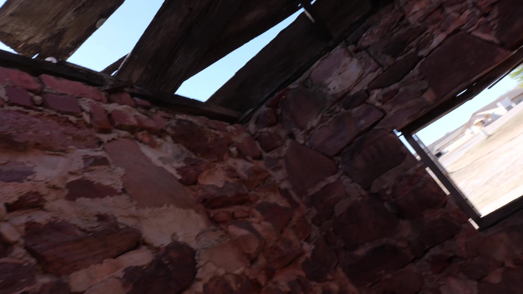 Rough stone wall and wooden beams inside a historic structure near Seaba Station Museum.