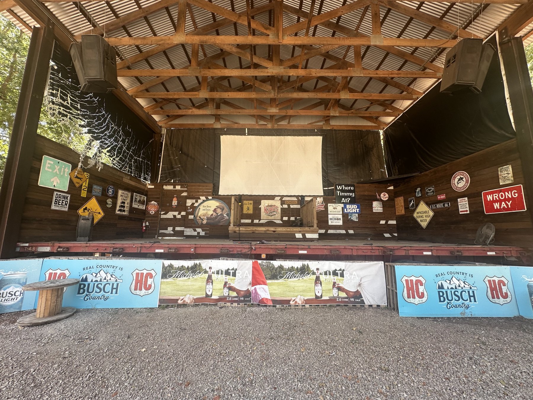 Covered outdoor stage at Hollywood Corners in Norman, Oklahoma, with wood beams and signs.