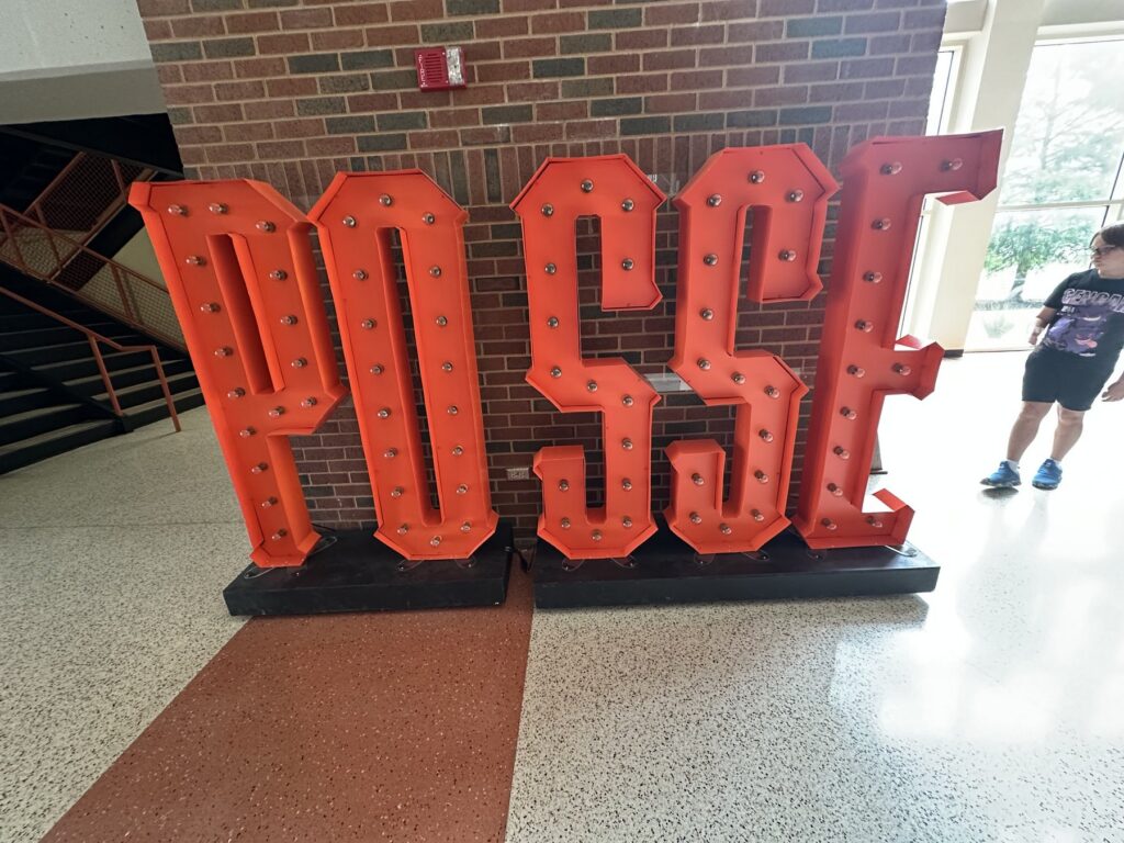 Large orange POSSE letters displayed inside an Oklahoma State University athletics building.