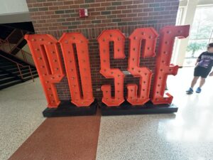Large orange POSSE letters displayed inside an Oklahoma State University athletics building.