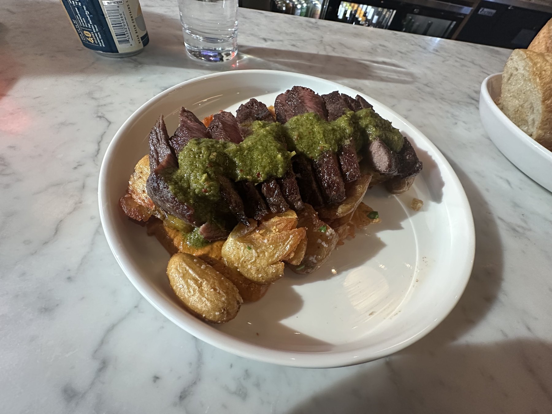 Sliced steak with green sauce over crispy potatoes at Red Rooster in Oklahoma City