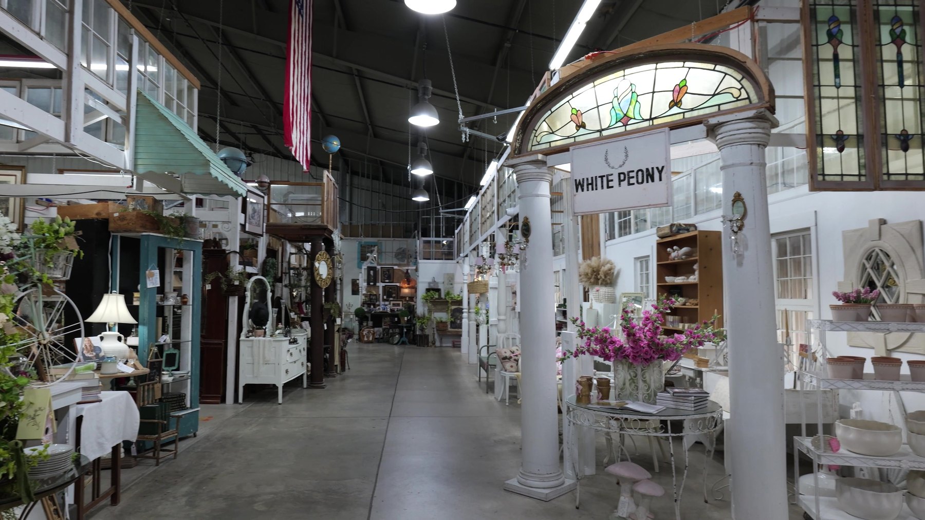 Wide interior aisle with vintage furniture and stained glass at The Rink Gallery in Bethany, Oklahoma.