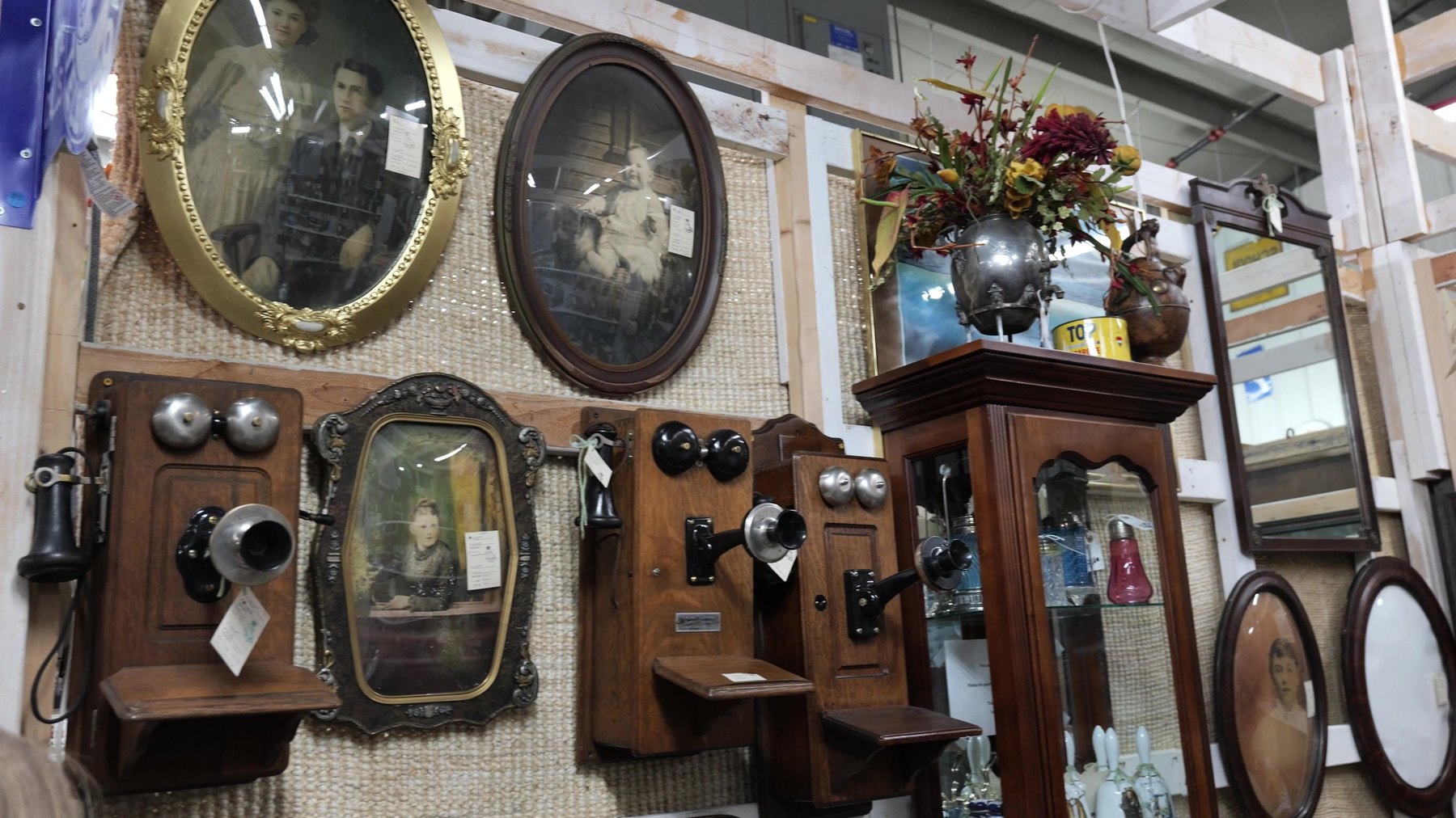 Wooden antique wall telephones and framed portraits at The Rink Gallery in Bethany, Oklahoma.