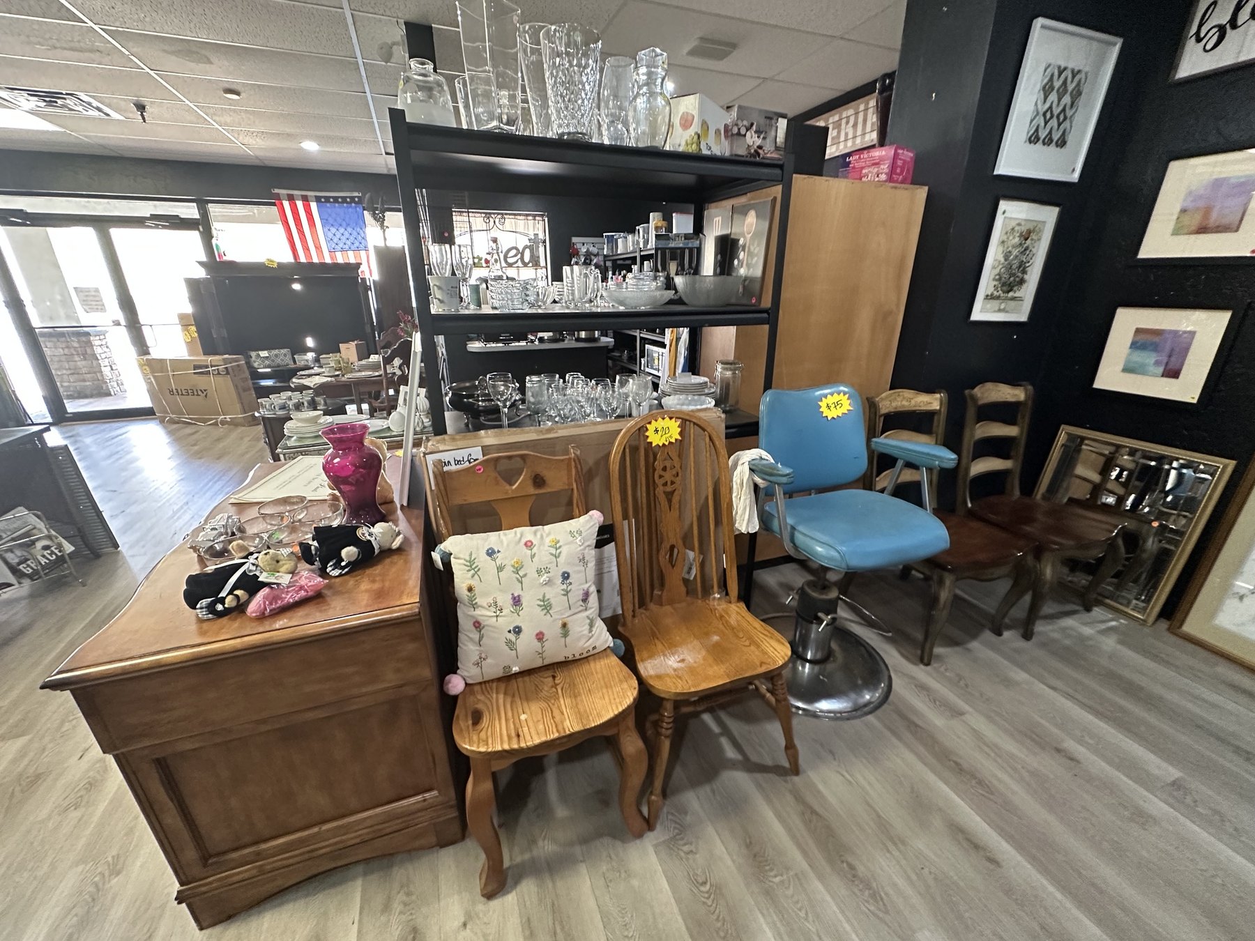 Furniture and decor display at Second Chances Thrift Store with chairs, framed art, glassware, and home items.