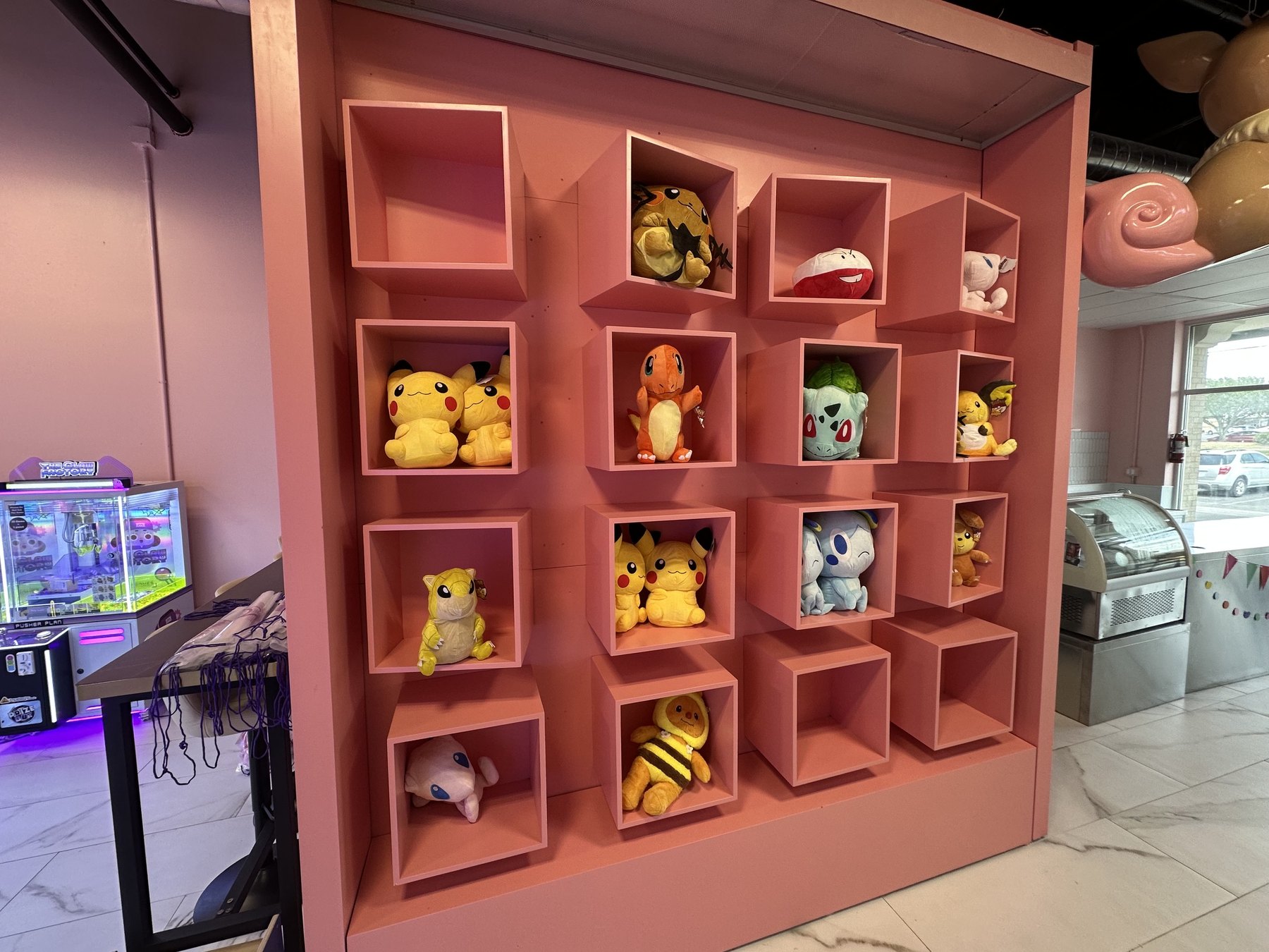 Pink cubby shelves filled with plush character toys at The Claw Factory in Edmond.