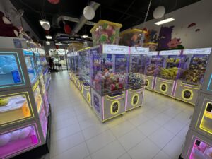 Rows of glowing claw machines filled with plush prizes inside The Claw Factory in Edmond, Oklahoma.