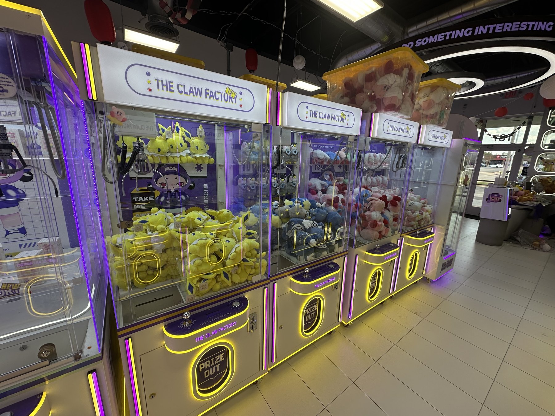 Claw machines filled with yellow and pastel plush prizes at The Claw Factory in Edmond.