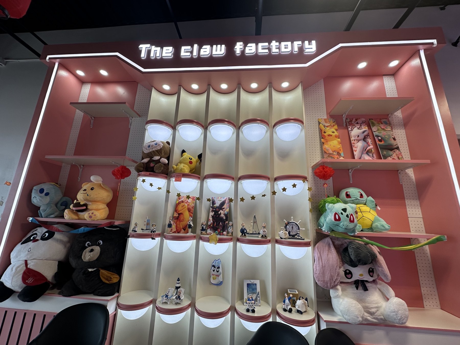 Pink prize display wall with plush toys and collectible figures inside The Claw Factory in Edmond.