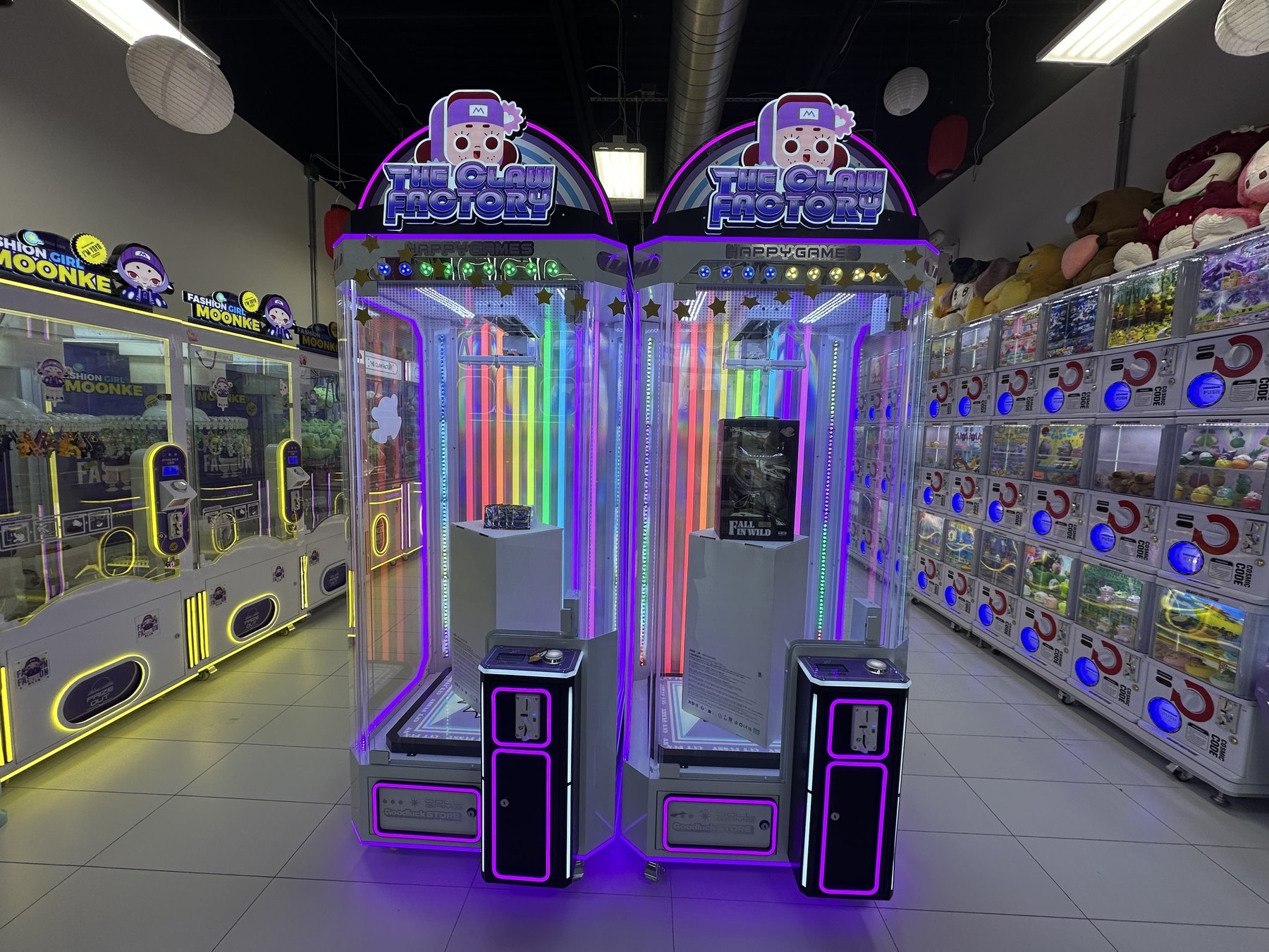 Two neon-lit Happy Game prize machines inside The Claw Factory arcade in Edmond.