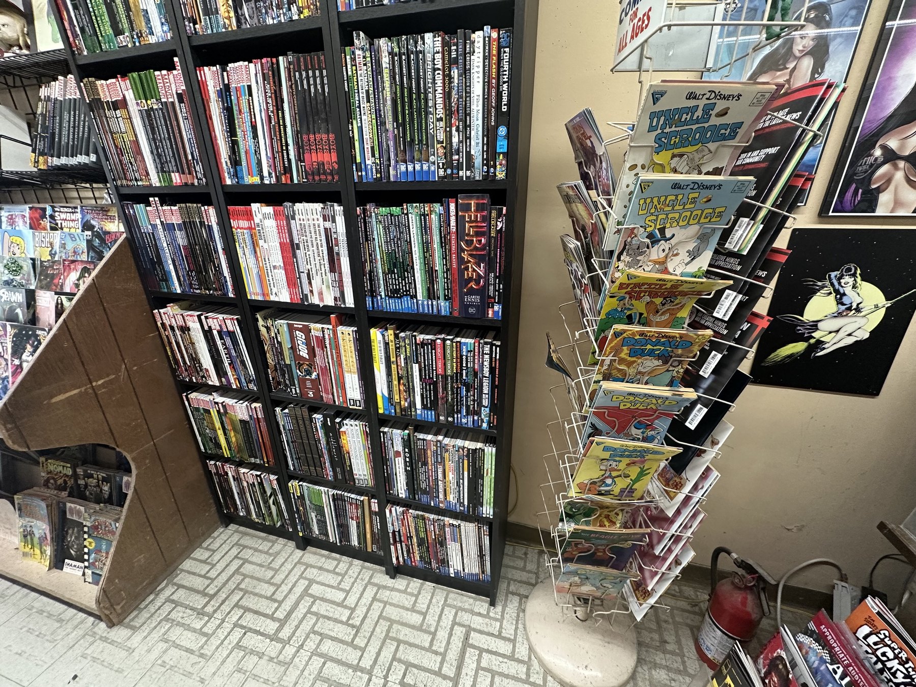 Graphic novels and classic comic books on shelves and a spinner rack at The Comic Empire