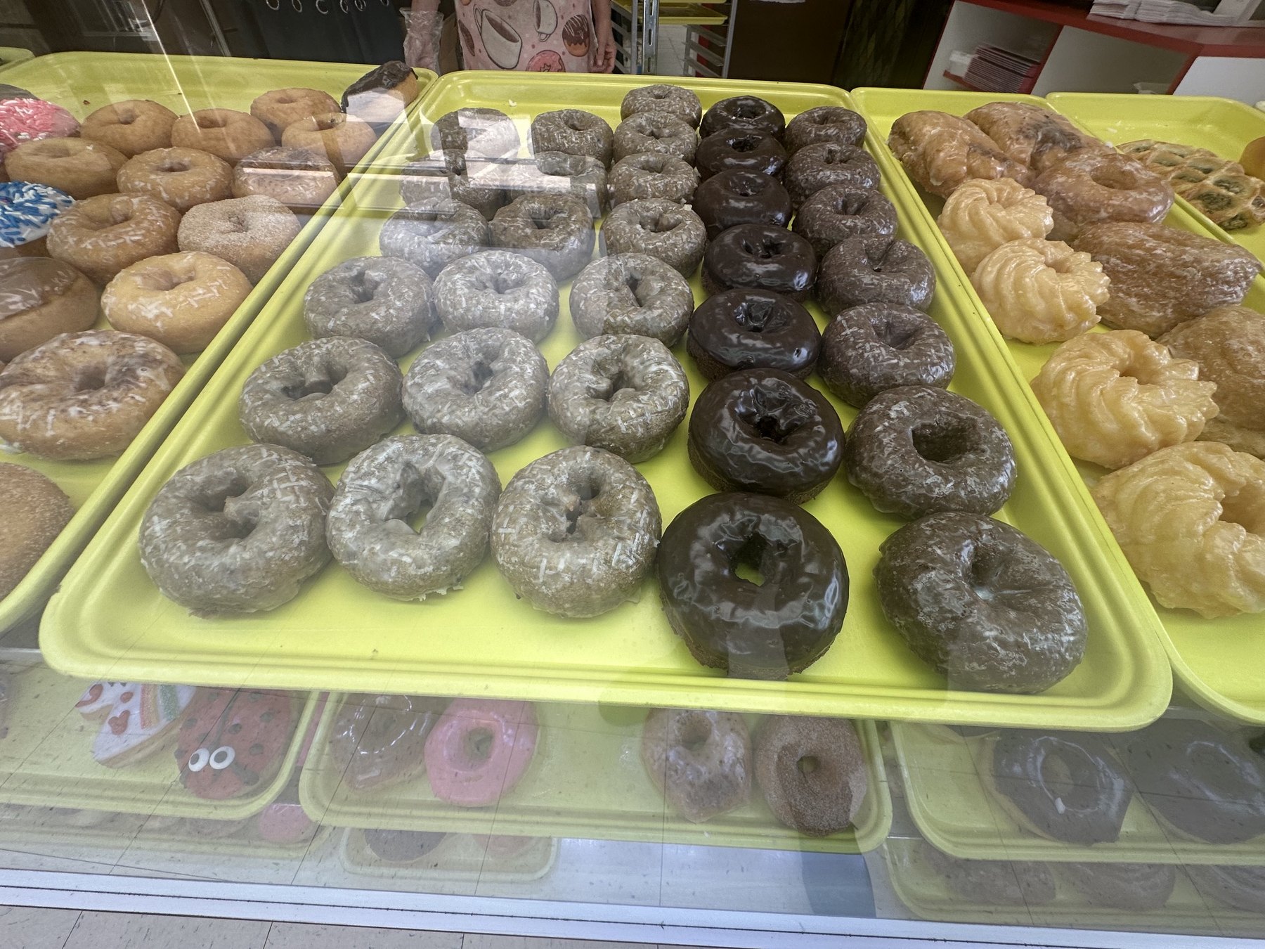 Classic glazed, powdered, and chocolate donuts in the Wow Donuts display case in Edmond
