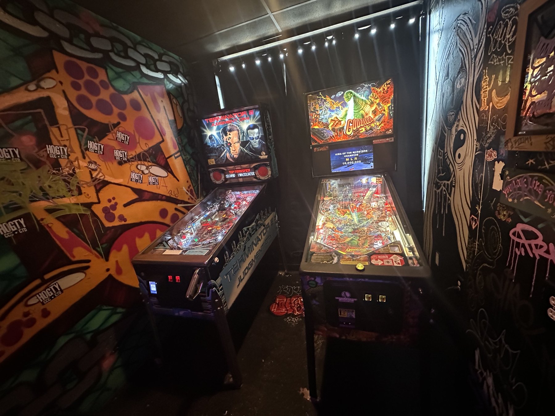 Two pinball machines inside a graffiti-covered corner at Rad Bar in Oklahoma.